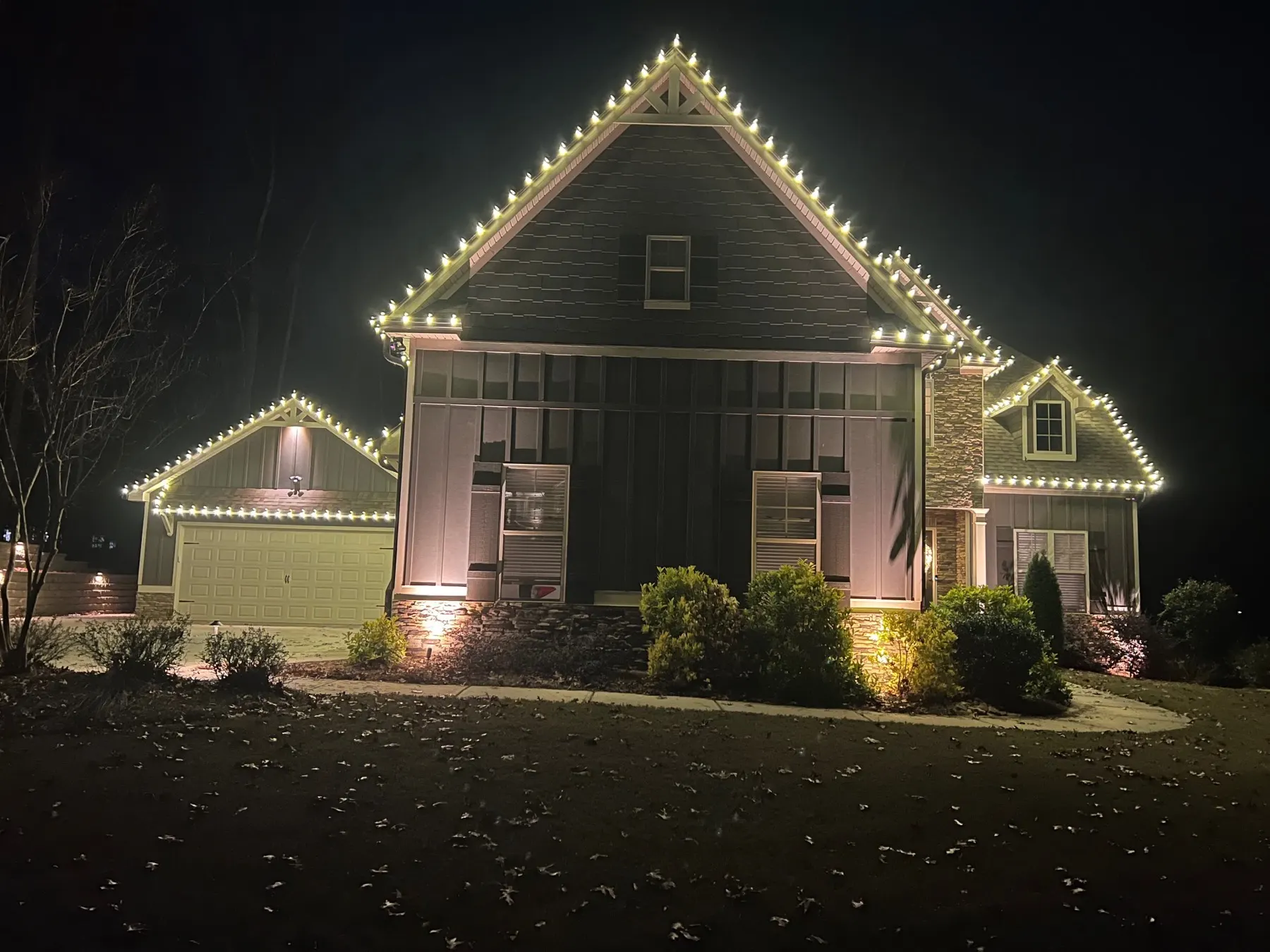 Two-storey home lit at night with warm white C9 bulbs following every gable and the full front roofline in one continuous, evenly spaced run