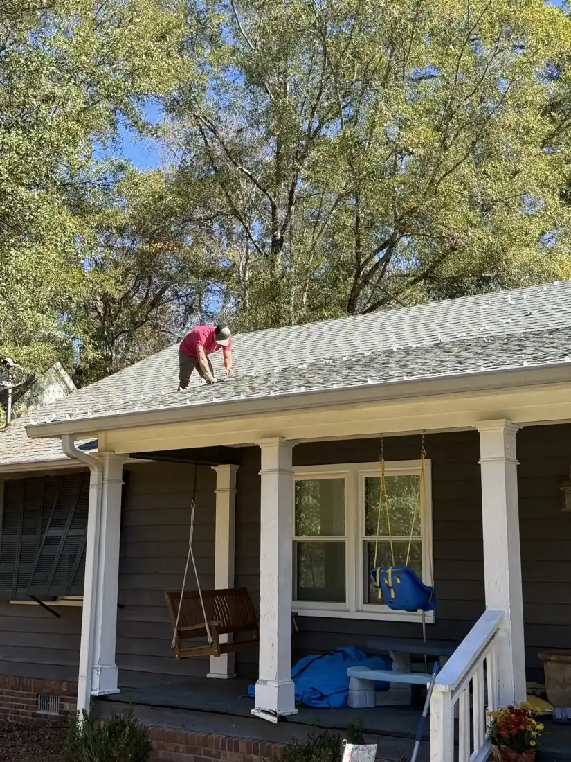 AJ Phillips working along the roof edge above a covered porch, setting an evenly spaced run of clips across the full front of the house