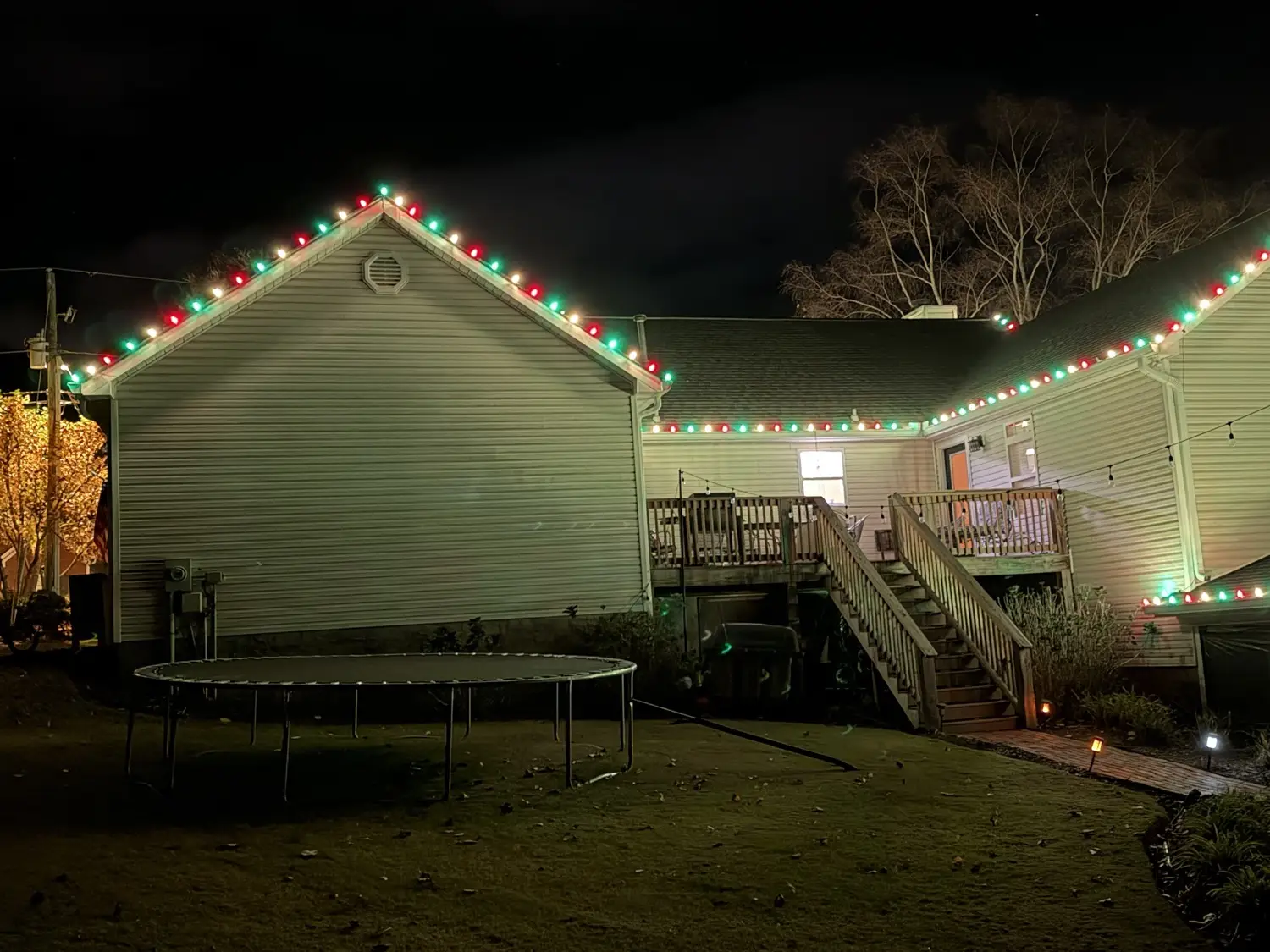 Side gable of a home at night outlined in alternating red and green C9 bulbs, the run carrying unbroken around the corner and along the eave