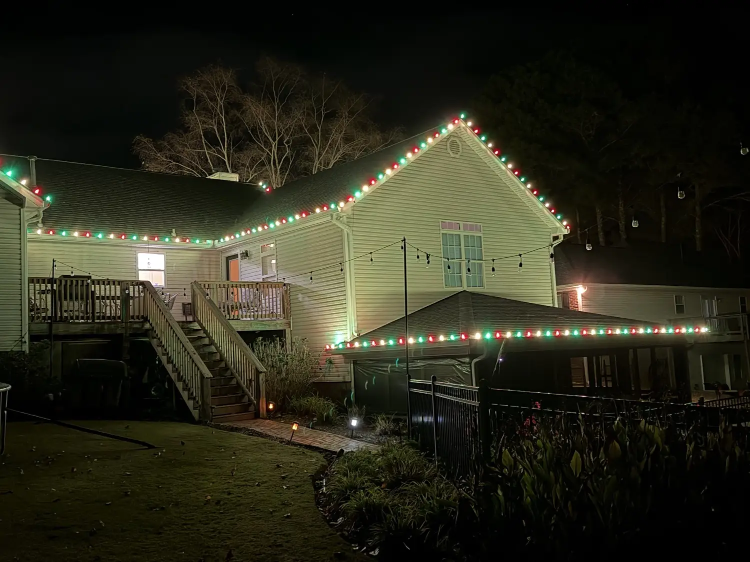 Two-storey home at night with alternating red and green C9 bulbs following the rear gables, the eave line and the roof of the lower porch